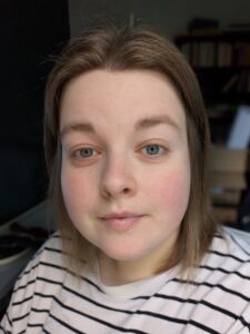 Headshot of Caitlin, with short brown hair and wearing a stripy shirt.