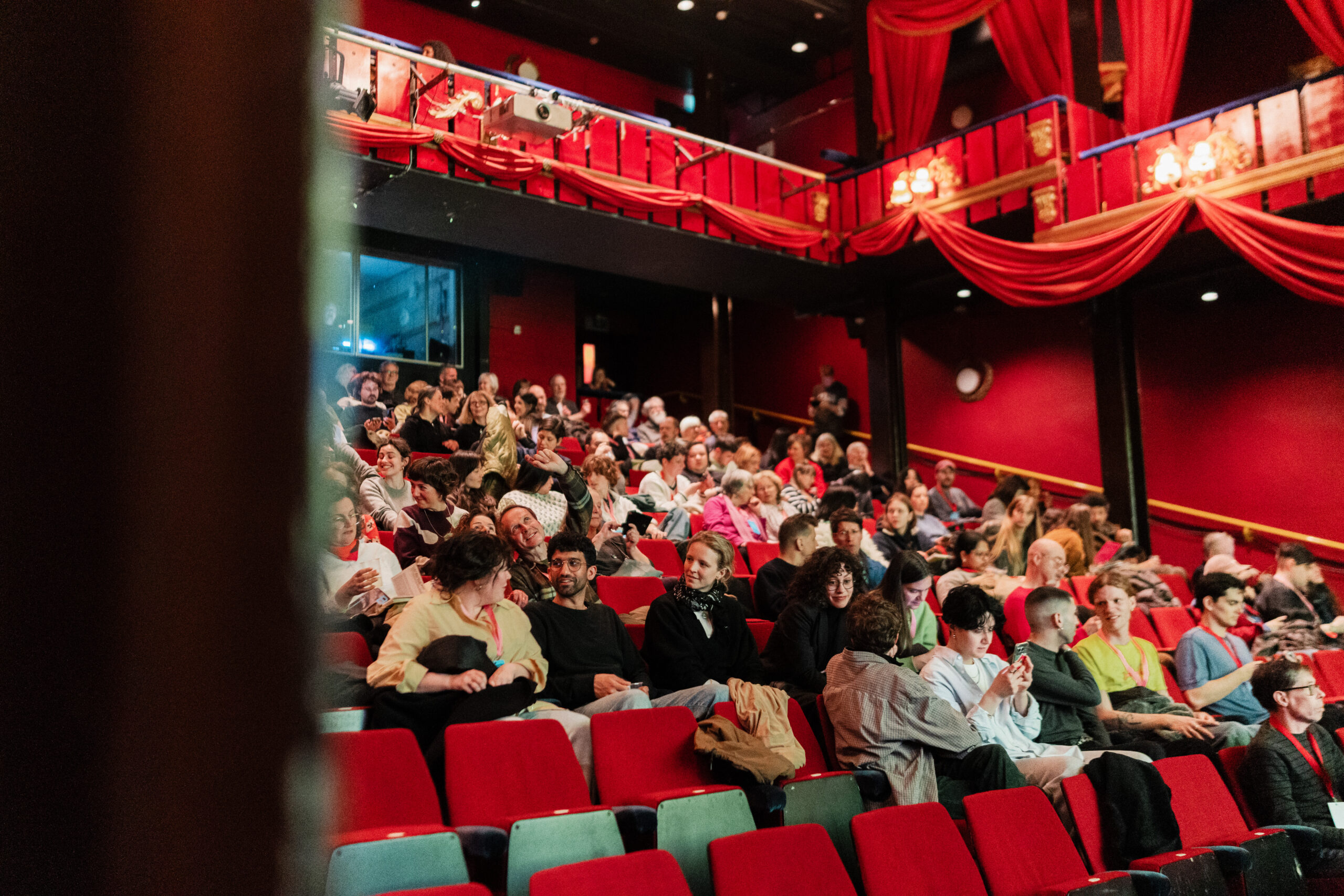 Cinema audience applauding. Deep red upholstery and walls.
