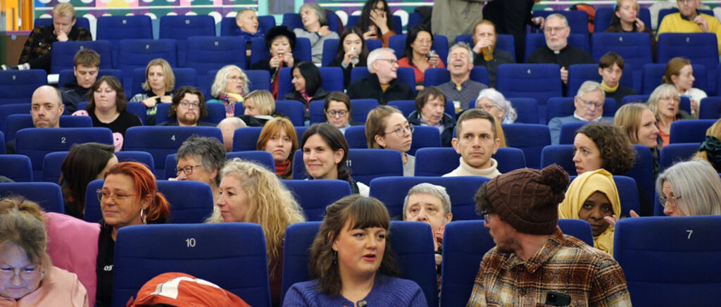 a group of people in a cinema with blue seats