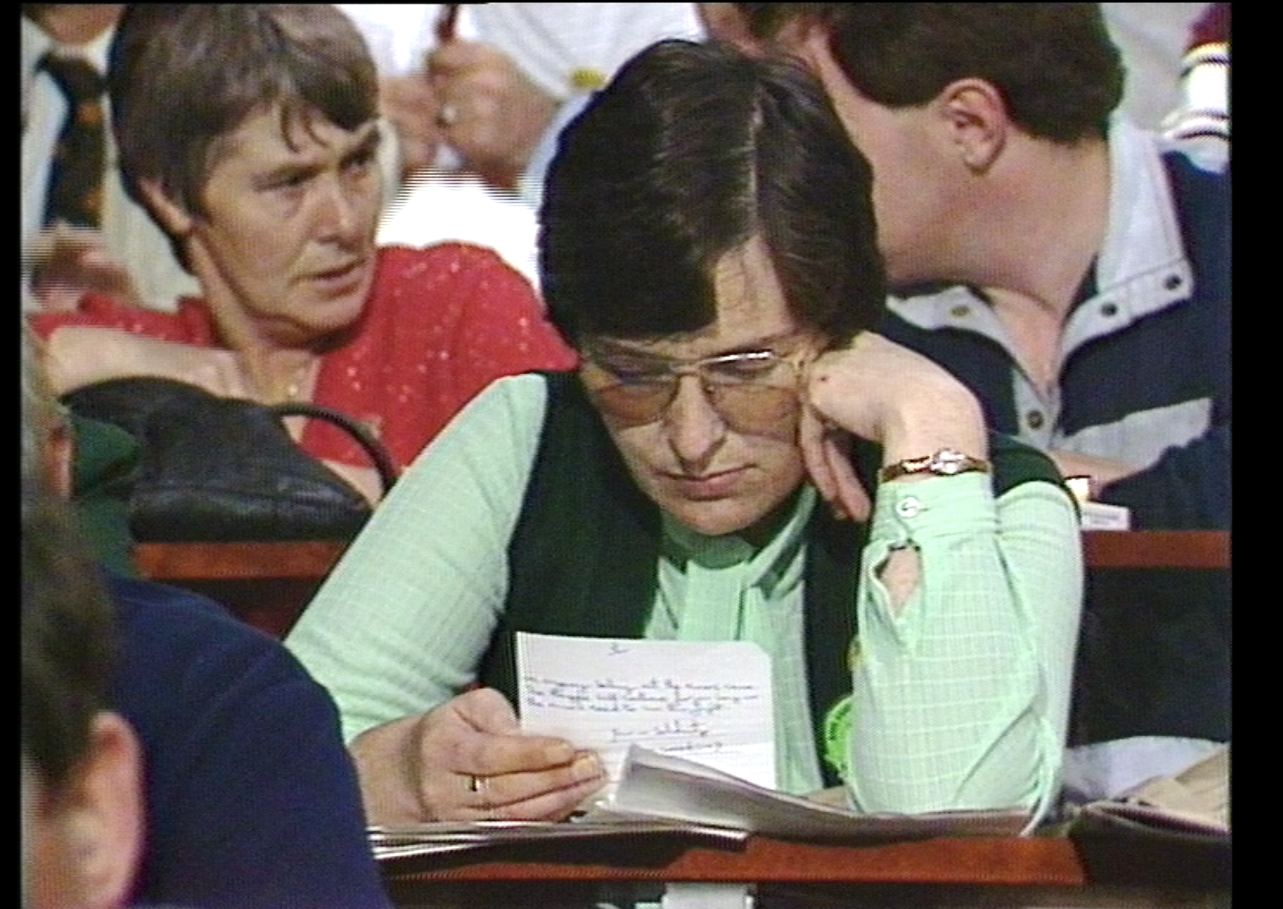 a woman in a pale green shirt studies a piece of note paper