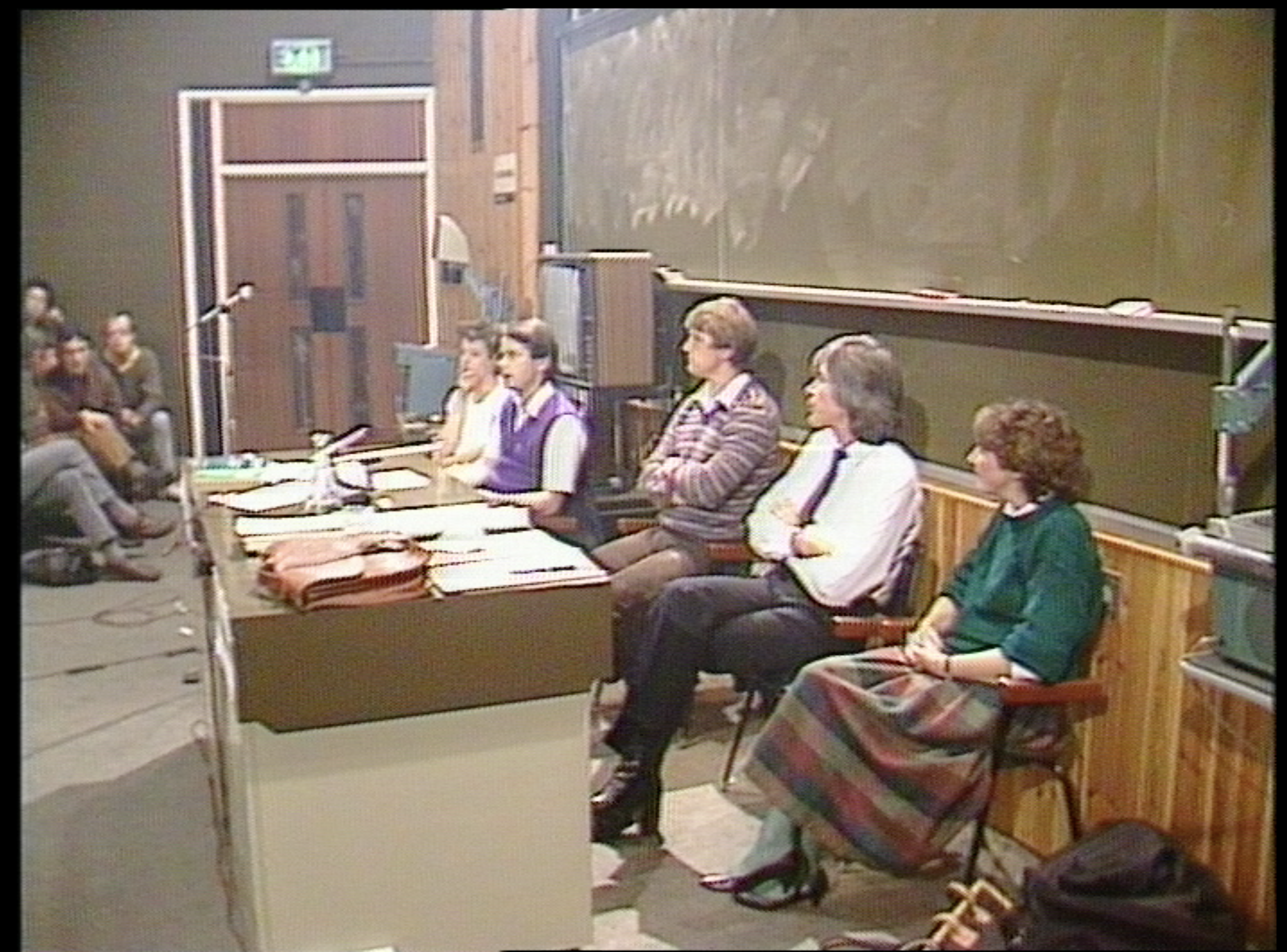 a row of people sat in front of a table in a brownish room
