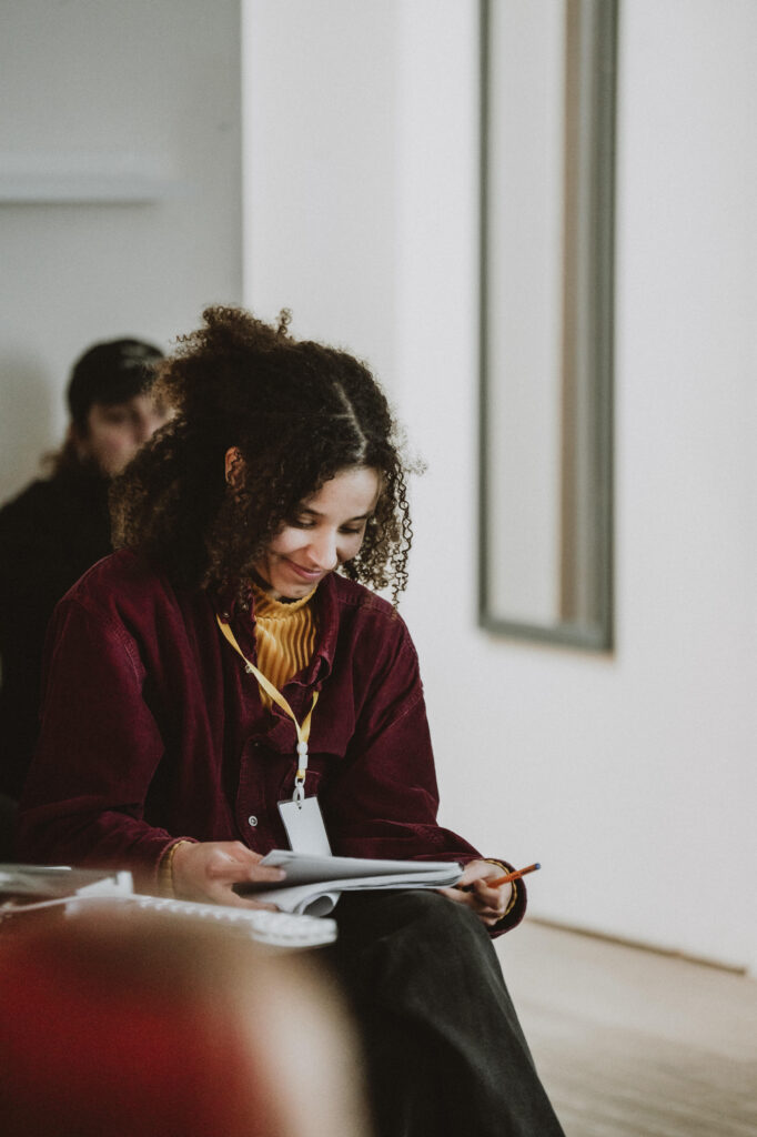 Miranda smiling looking down at a piece of paper wearing a red shirt