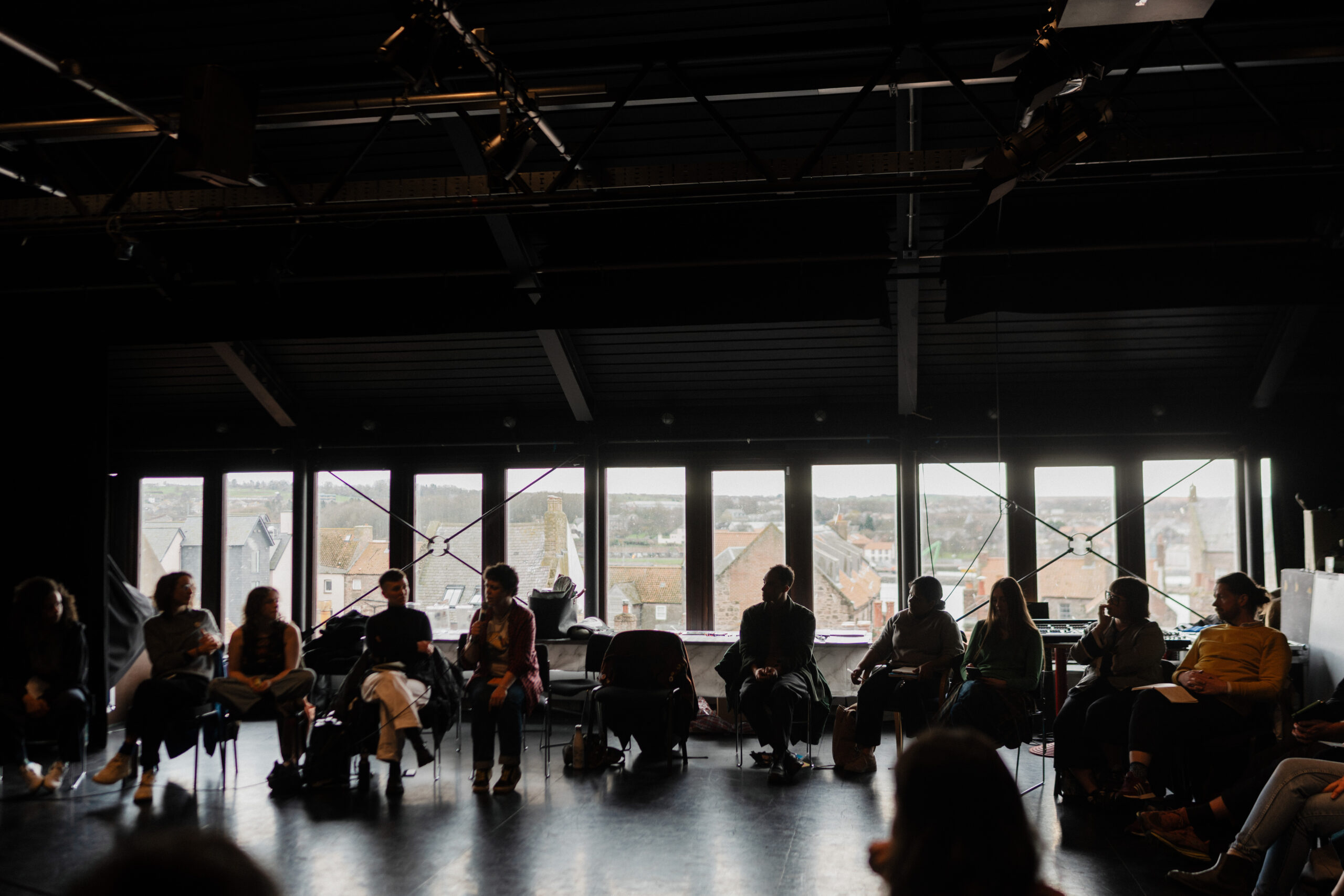 silhouettes of people seated in front of a long window in a darkened room